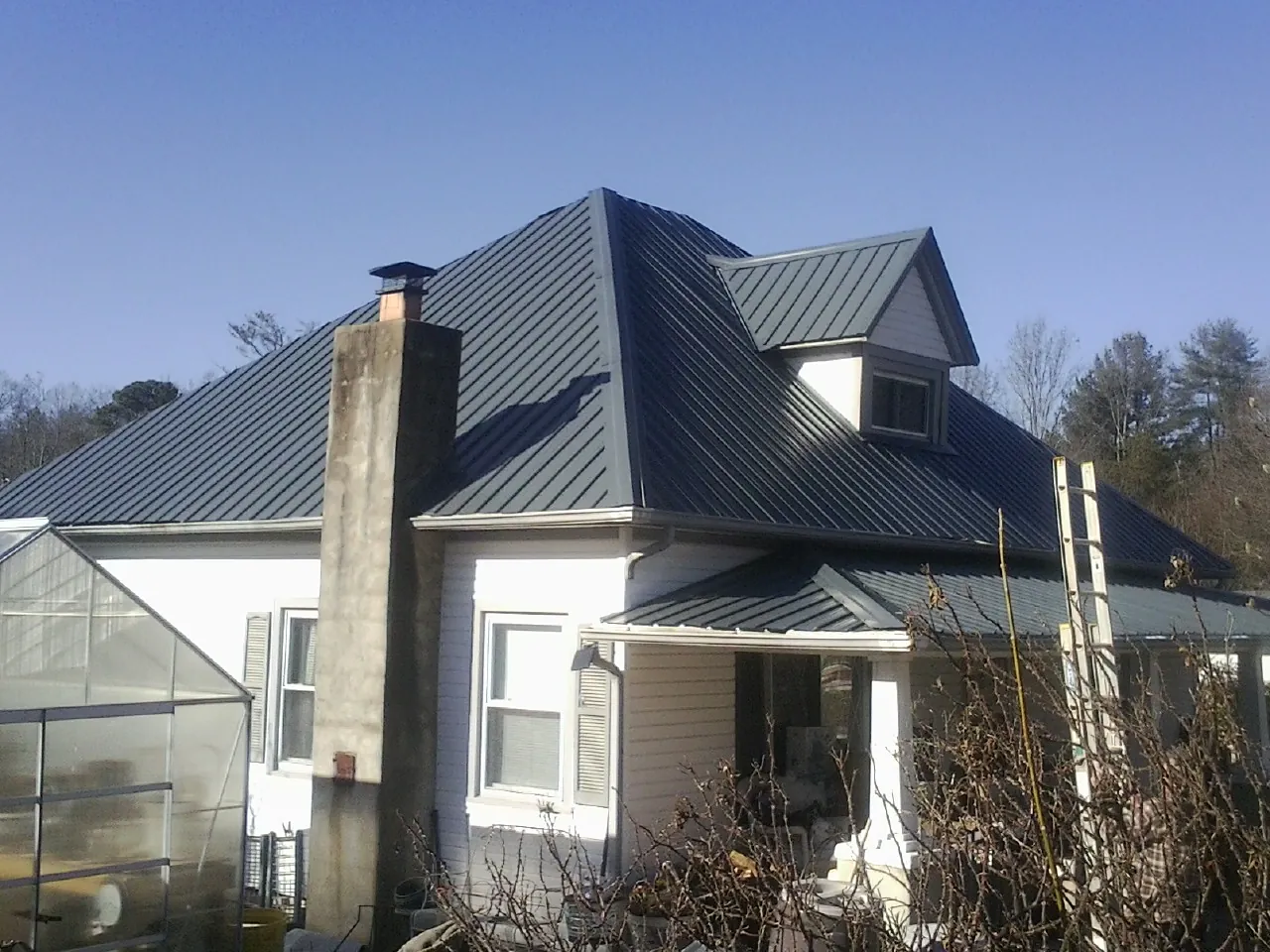 Dark blue standing seam metal roof on a white farmhouse with dormer — Slate & Tile Roof Repair by Roofing Brothers in Lake Elsinore