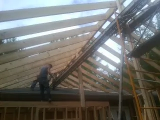 Rafters going up over a new addition with a worker on the wall in Lake Elsinore