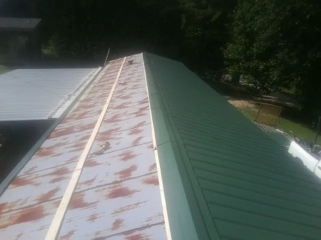 Old rusted panels beside newly installed green metal roofing — Wind Damage Roof Repair by Roofing Brothers in Lake Elsinore