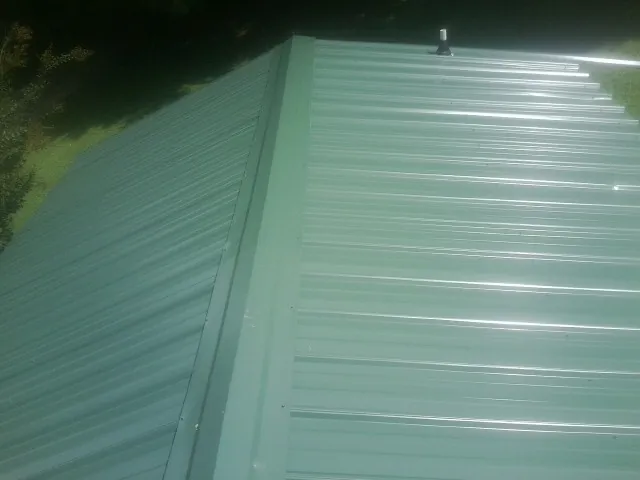 New green metal panels meeting at the ridge of a roof — Flat Roof Repair work by our crew in Lake Elsinore