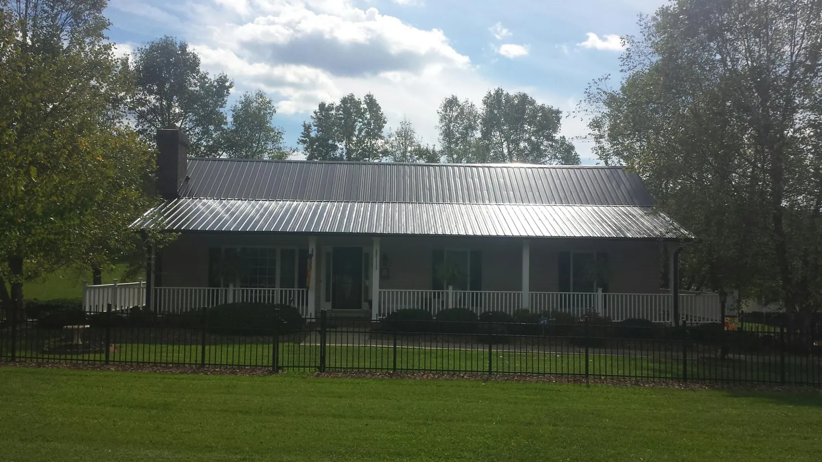 Gray metal roof on a brick ranch with a full width front porch — Gutter Guard Installation work by our crew in Lake Elsinore