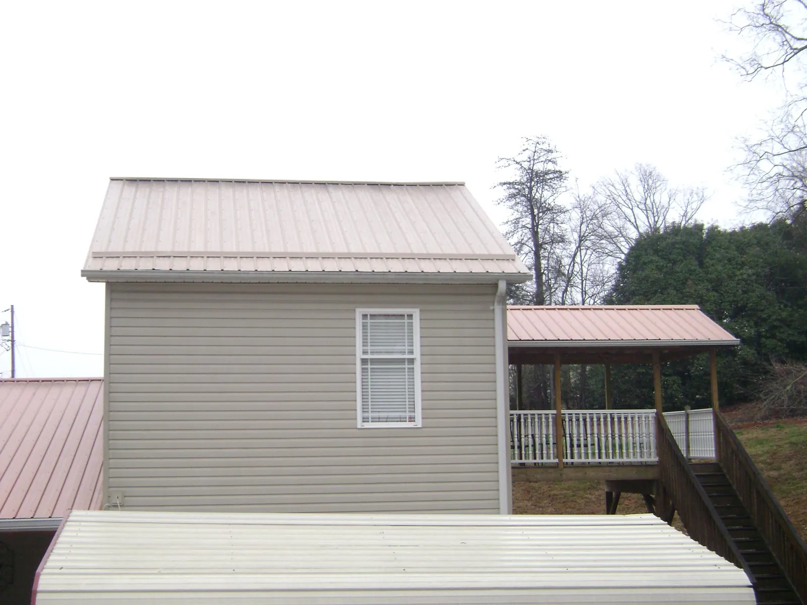Tan metal roofs on a two story addition and attached porch, from a Roof Replacement job in Lake Elsinore
