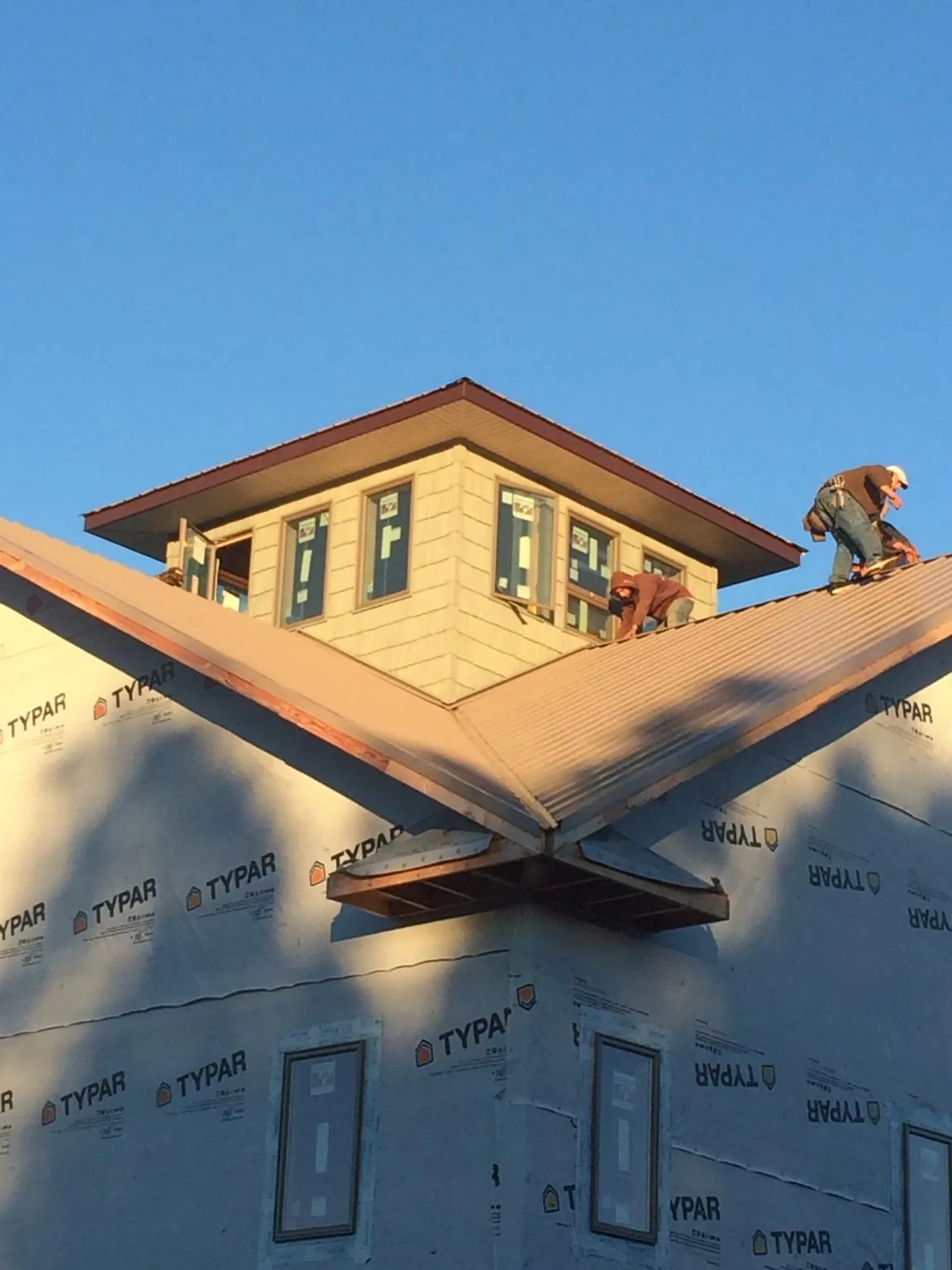 Roofers working around a rooftop cupola on a new metal roof at sunset — Roof Waterproofing in Lake Elsinore by Roofing Brothers